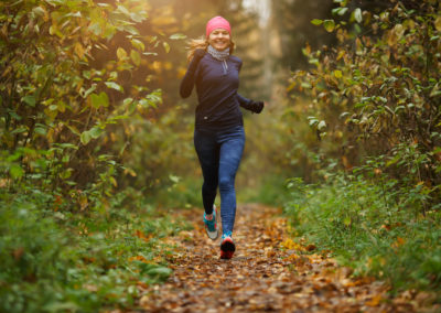 Une jeune femme blonde court sur un sentier forestier